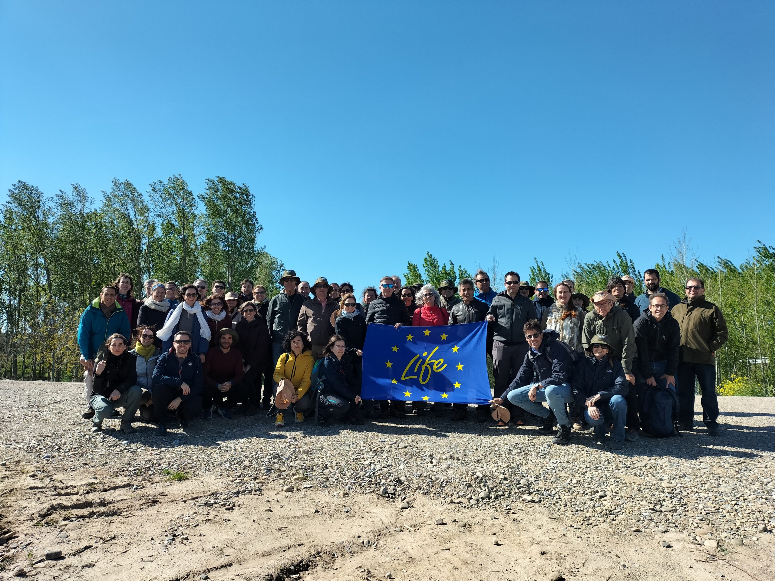 Foto de grupo con bandera LIFE visita Organismos de cuenca de toda España al meandro de La Roza, Alfaro.